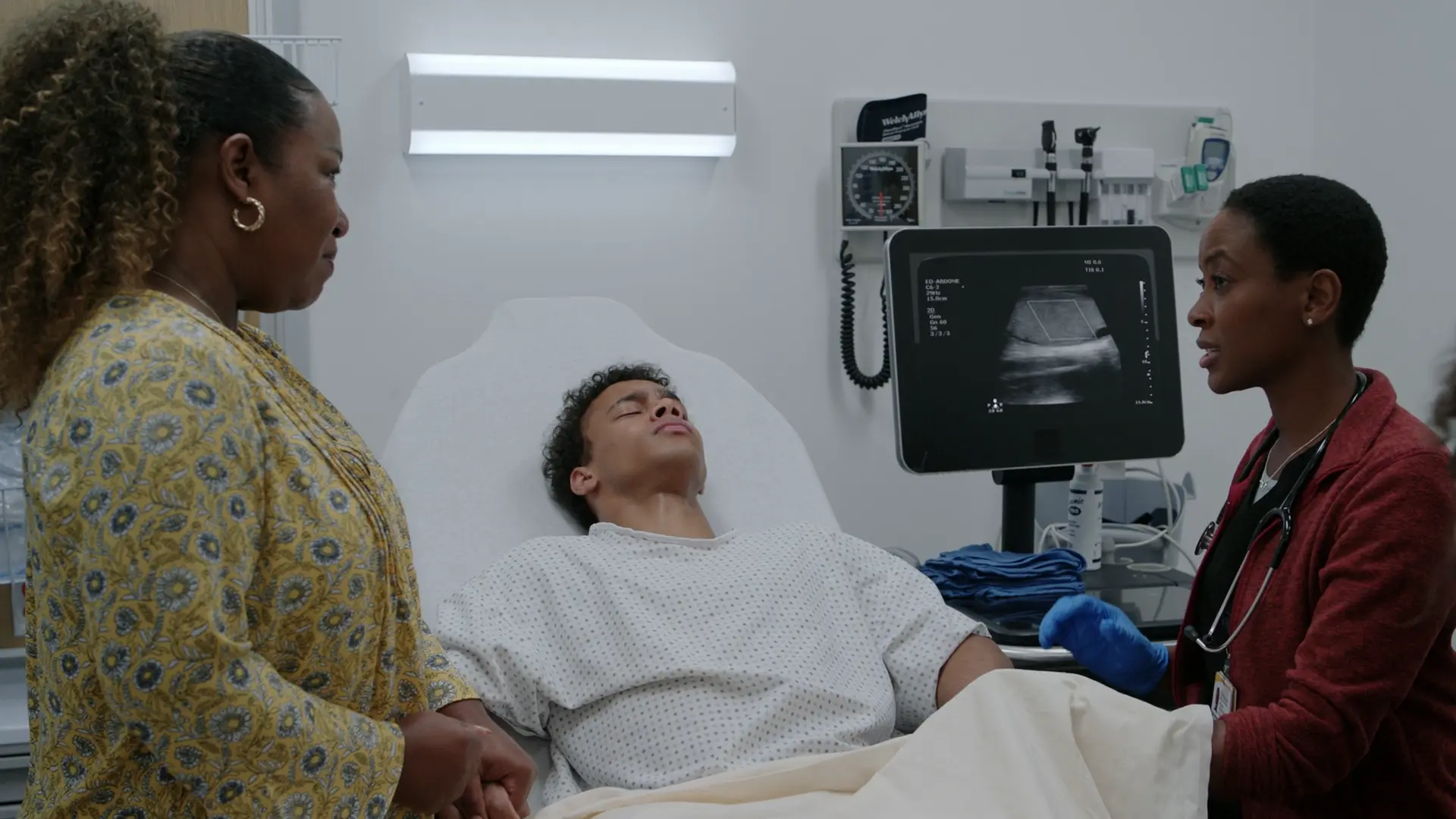 Dr. Collins führt bei Dillon, der sichtlich Schmerzen hat, am Bett eine Point-of-Care-Ultraschalluntersuchung des Skrotums durch. Der Monitor zeigt deutlich ein Farbdoppler-Fenster über dem Hoden mit absolut keinen vaskulären Flusssignalen.