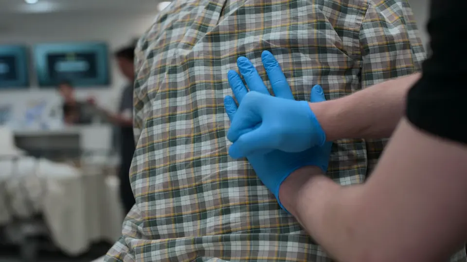 Profissional realizando a manobra de punho-percussão lombar (pesquisa do sinal de Giordano) no Sr. Green.